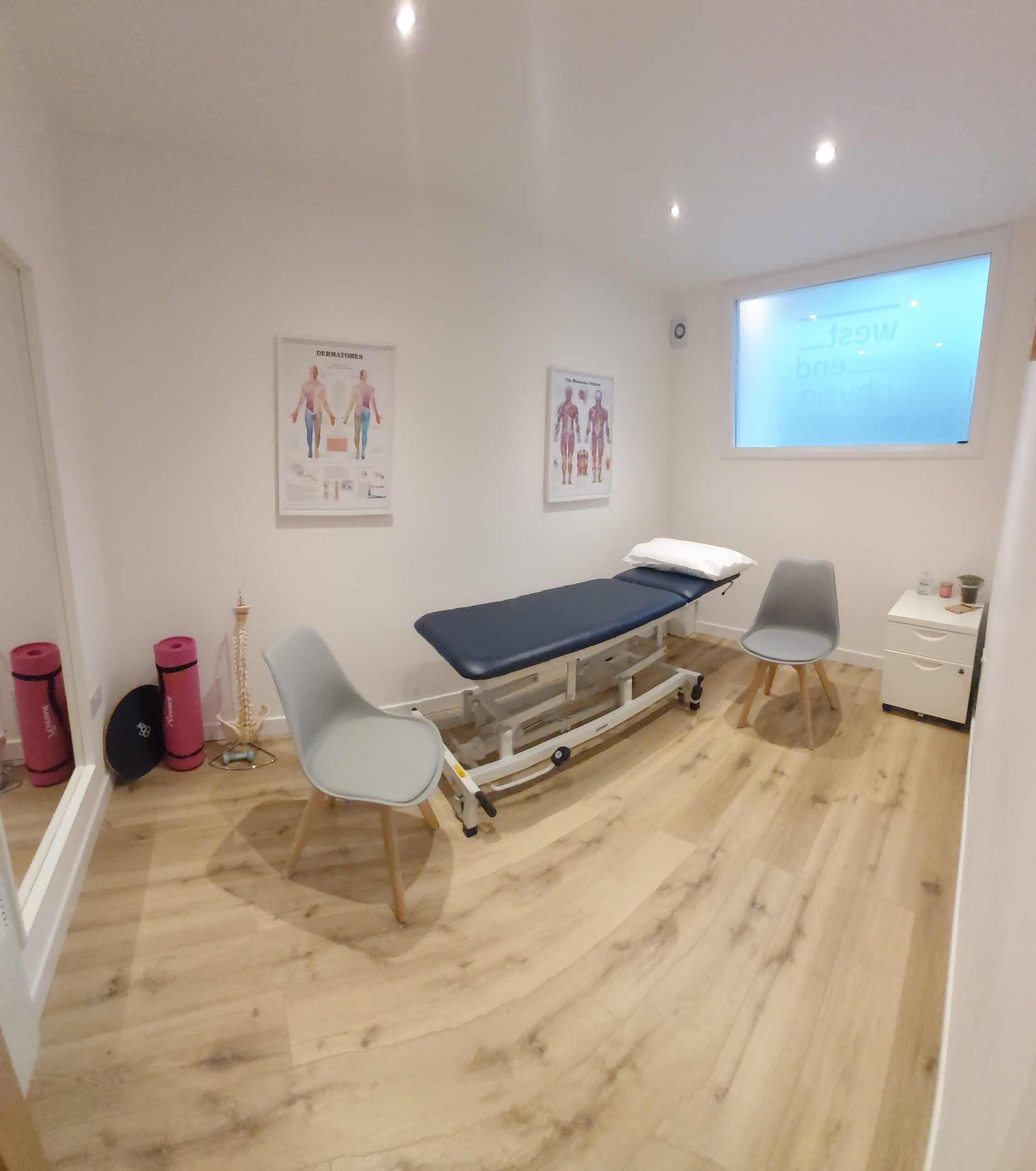 Professional treatment room at West End Physio, Glasgow. In the room there is a plinth, yoga mat and spine model.