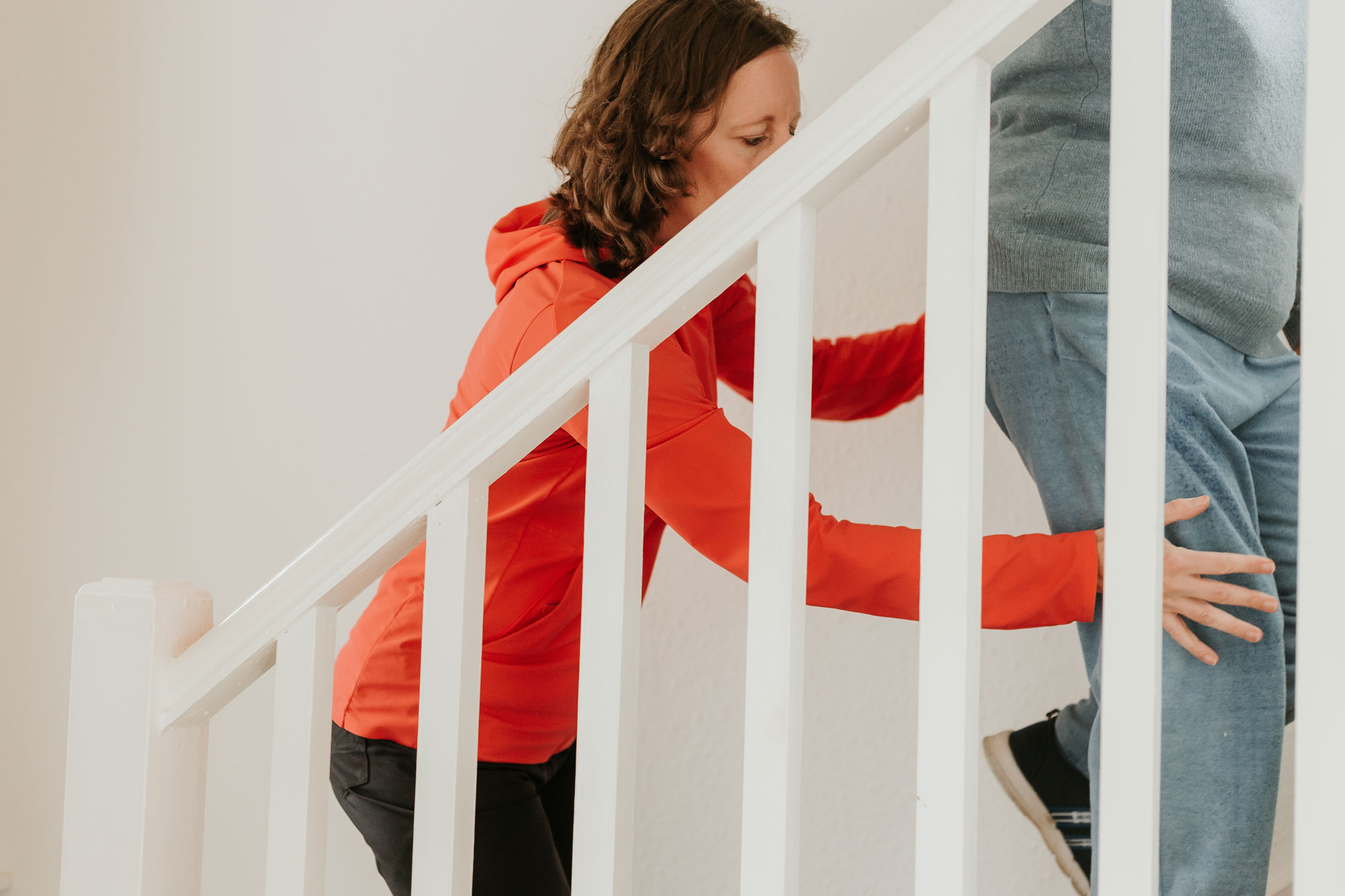 Physiotherapist assessing a patient as they ascend a flight of stairs during a home visit, focusing on mobility and safety